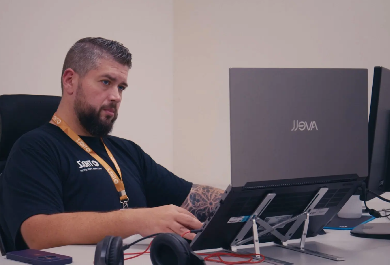 Assistência: Técnico da Tholz trabalhando em notebook em ambiente de assistência técnica, realizando análise e suporte técnico especializado.